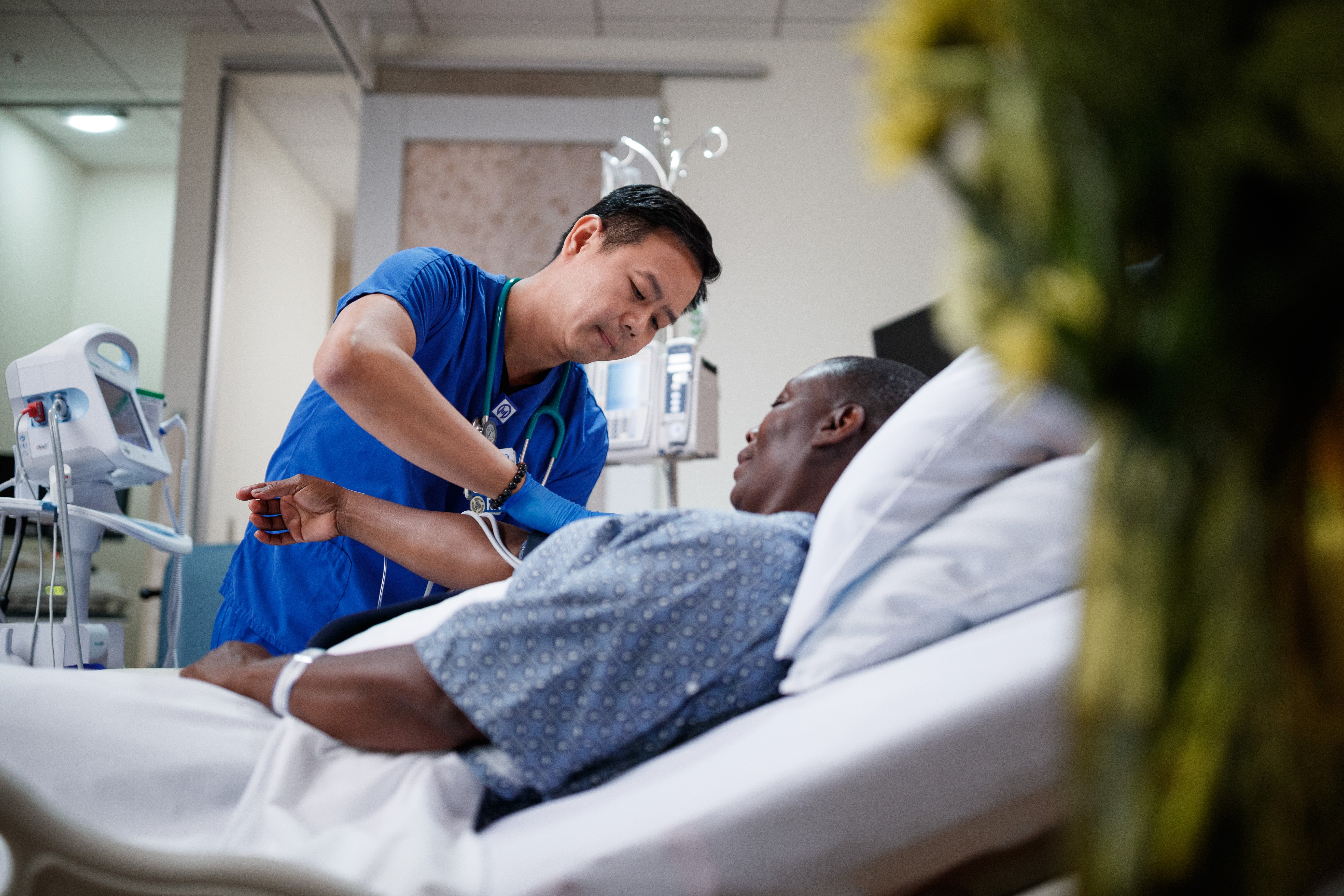 oncology nurse adjusting blood pressure cuff on patient in bed
