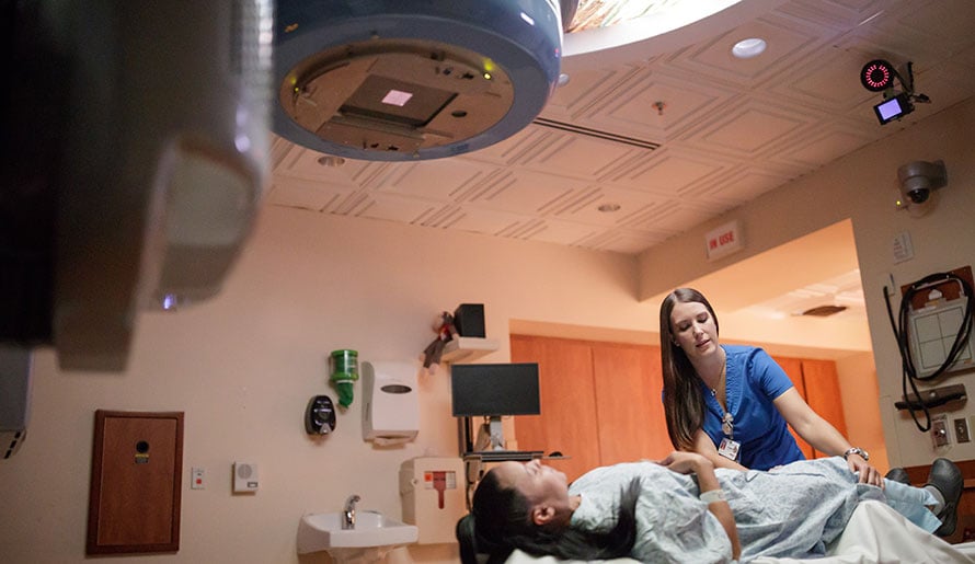 Nurse helps patient in radiation room at Moffitt