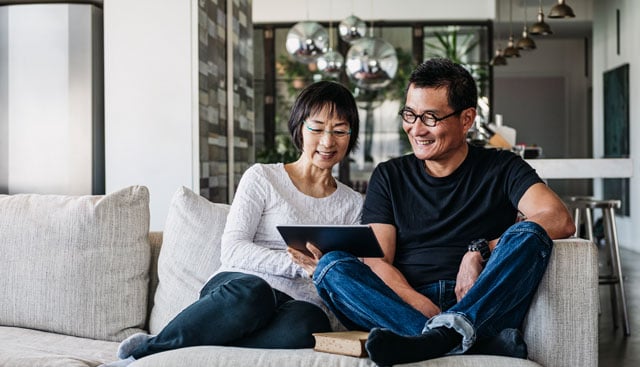 A couple at home reviewing insurance information using a tablet computer