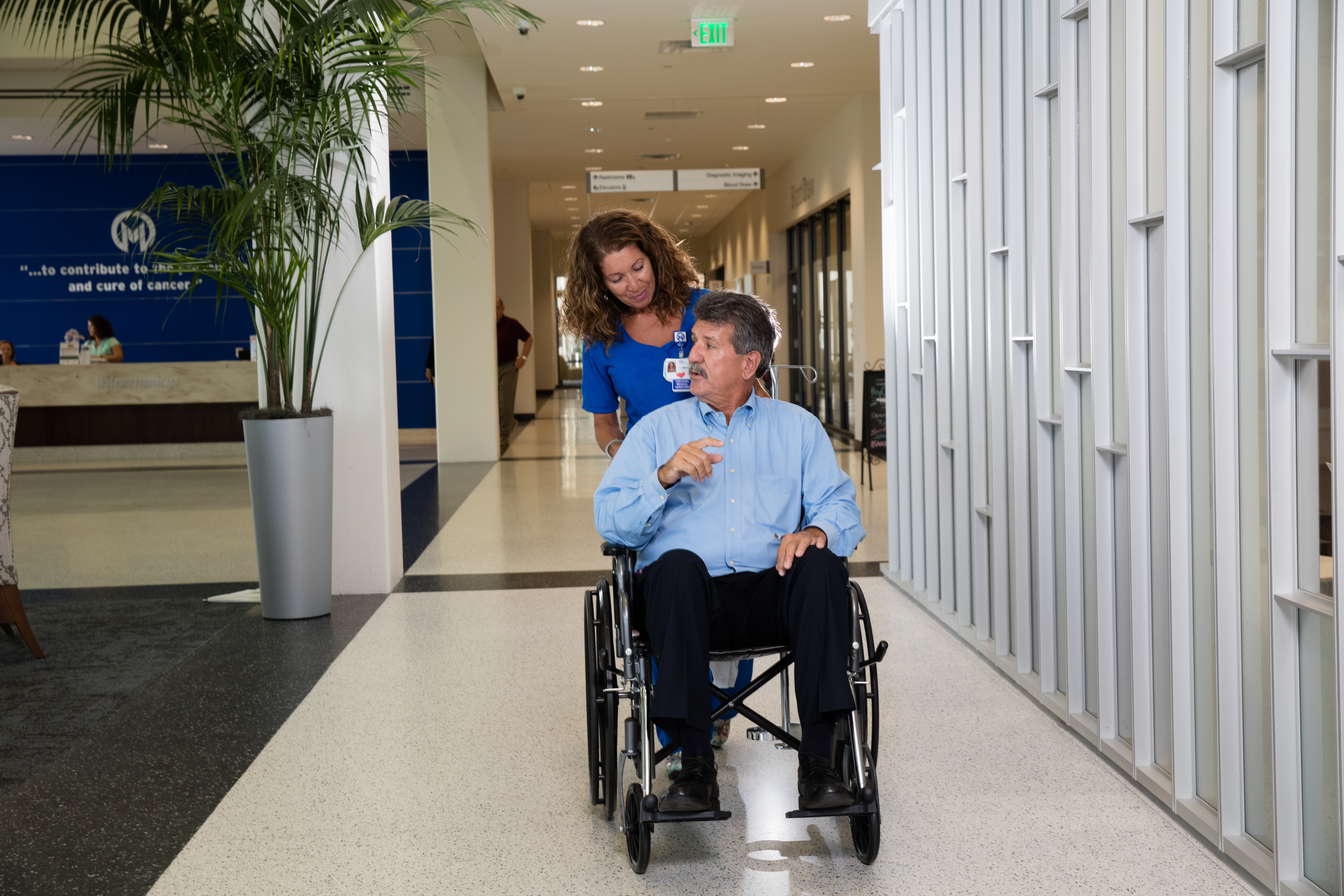 Certified Medical assistant talking with and pushing patient in wheelchair