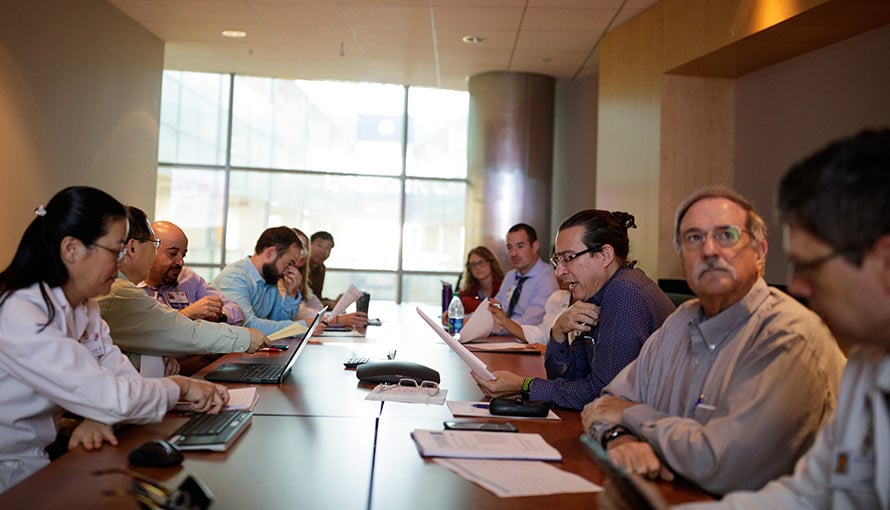 A group of doctors sit at a table during Moffitt's tumor board