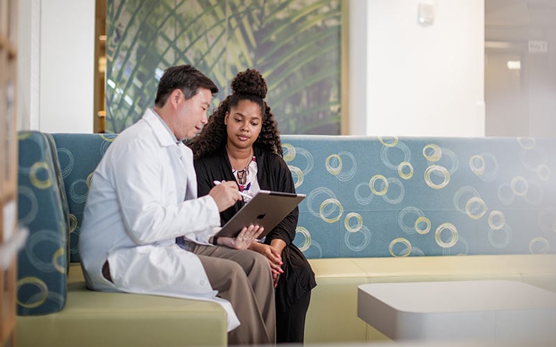 Doctor consulting patient while sitting on couch