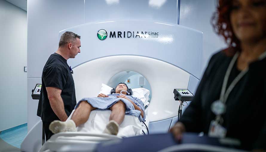 Image of a patient in the MRI Linac machine with two medical professionals assisting
