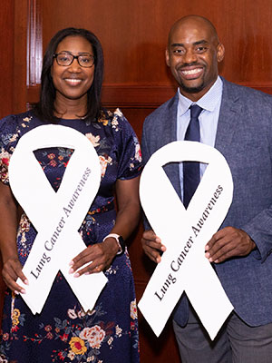 photo of Dr. Jhanelle Gray and Chris Draft holding white awareness ribbons
