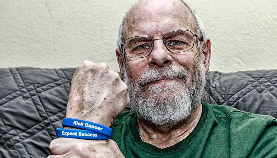 A man who had colon cancer shows bracelets with the words: Kick Cancer and Expect Sucess