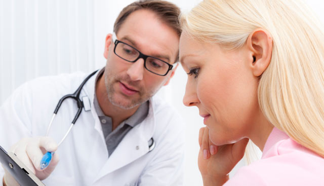 Doctor going over a skin cancer diagnosis with patient with blonde hair and fair skin