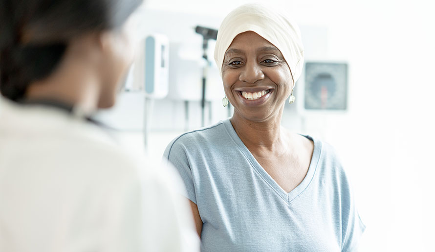 Patient with scarf on her head speaks with doctor