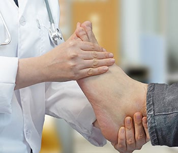 doctor examines the bottom of a foot for melanoma