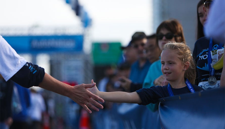A runner touches a child's hand during Miles for Moffitt