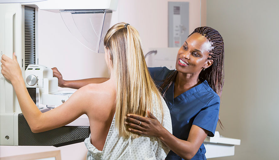 Moffitt nurse helping patient with mammography machine.