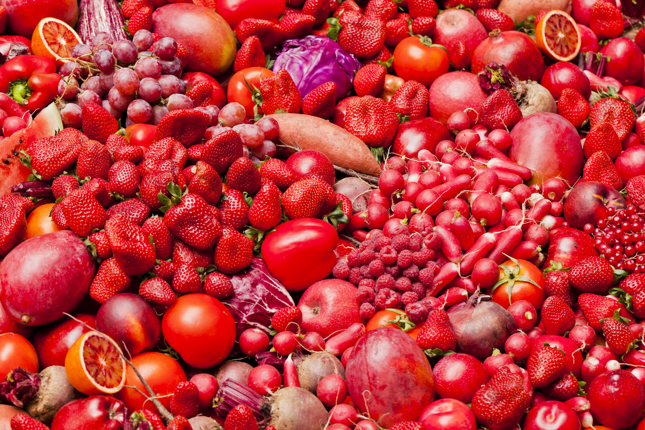 Pile of red fruits and vegetables including tomatoes, strawberries, peppers and more