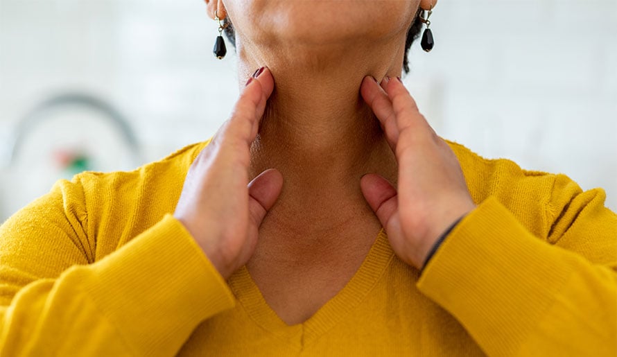 Woman feeling her neck for throat cancer symptoms