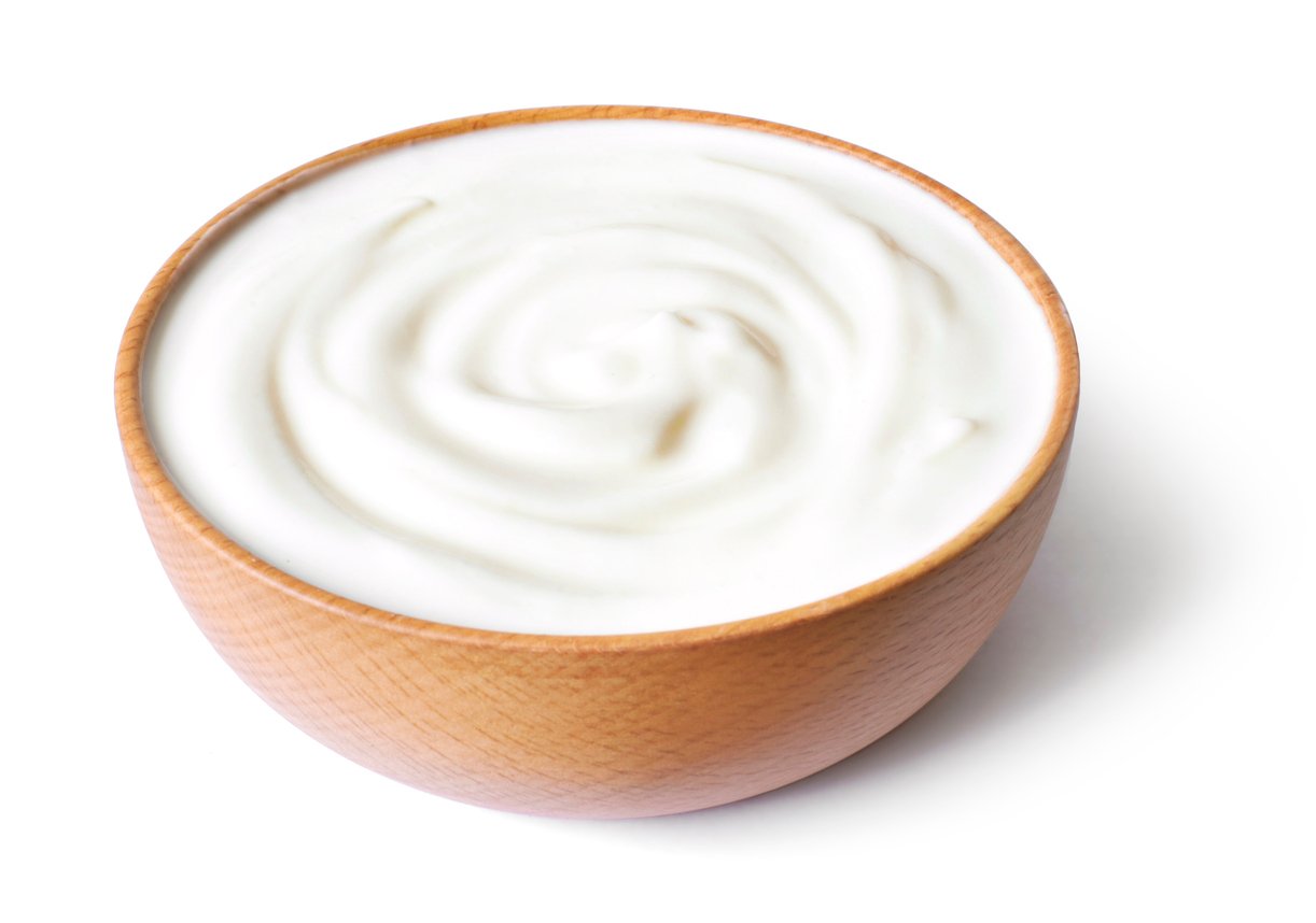 A wooden bowl filled with creamy yogurt on a white background.