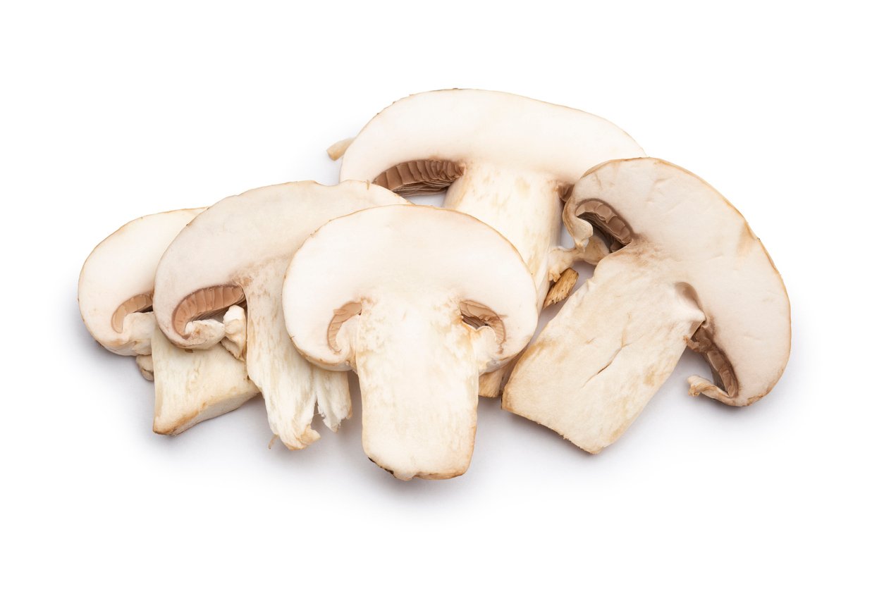 Sliced white mushrooms on a white background.