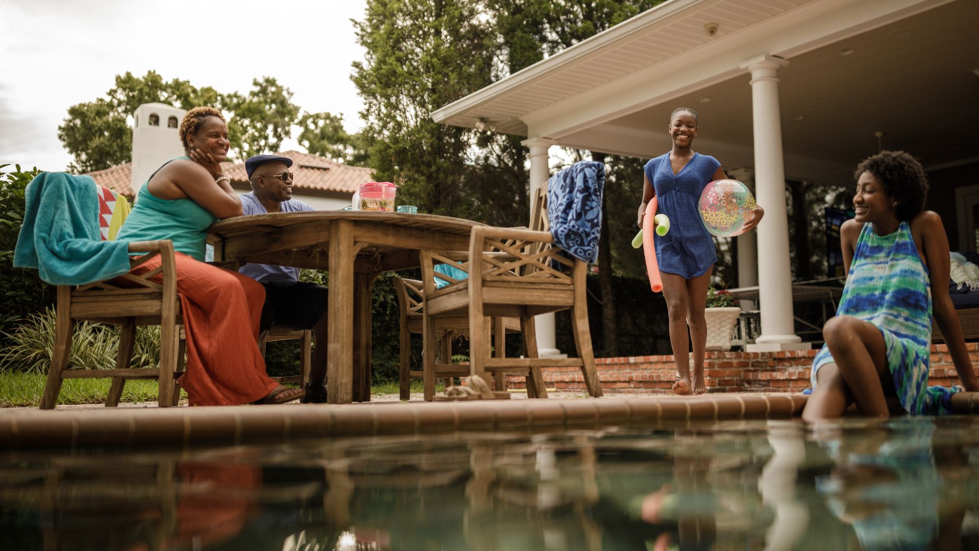 African American family sitting by pool.