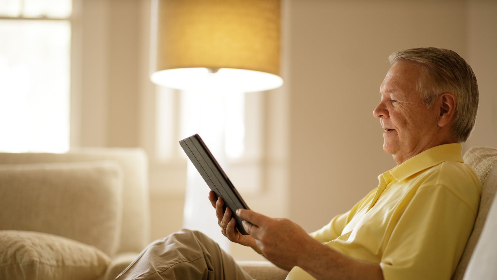 Man sits in recliner looking at tablet.