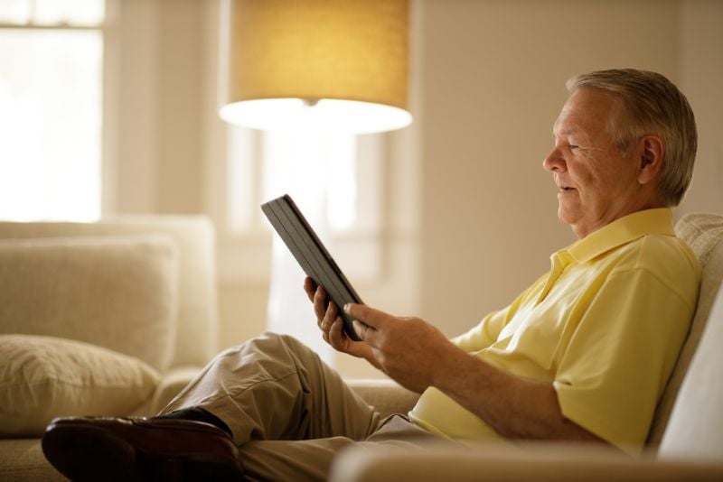 Man sitting in chair looking at tablet.