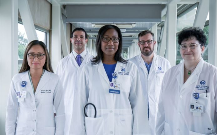 5 physicians standing together in white coats.