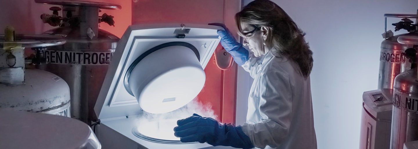 A woman cancer researcher for immunotherapy opens a piece of equipment.